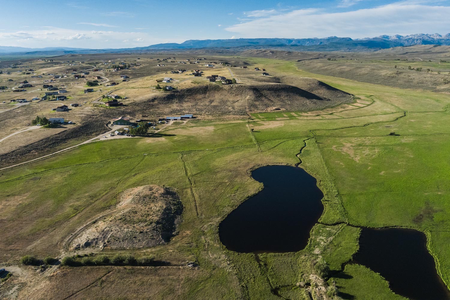 Aerial of the five-acre pond with the Wind River Range on the horizon