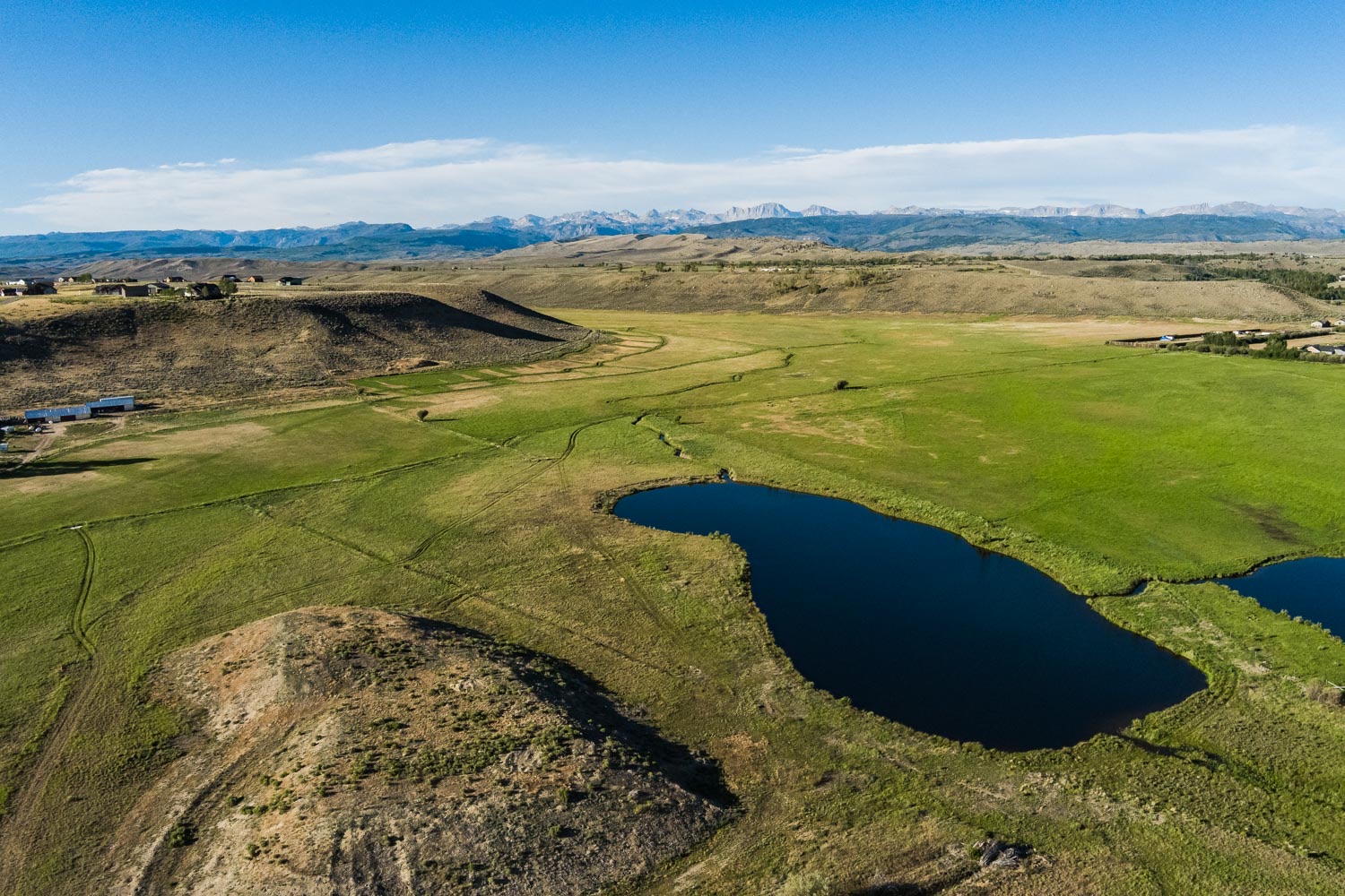 Aerial of the pond and open meadow with mountains beyond