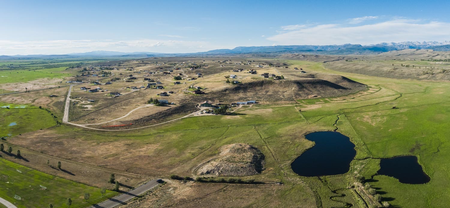 Wide aerial of the property, pond, and surrounding meadows