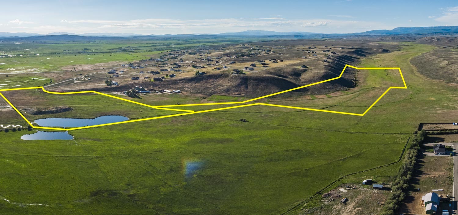 Aerial with the property boundary drawn, pond and mountains in view