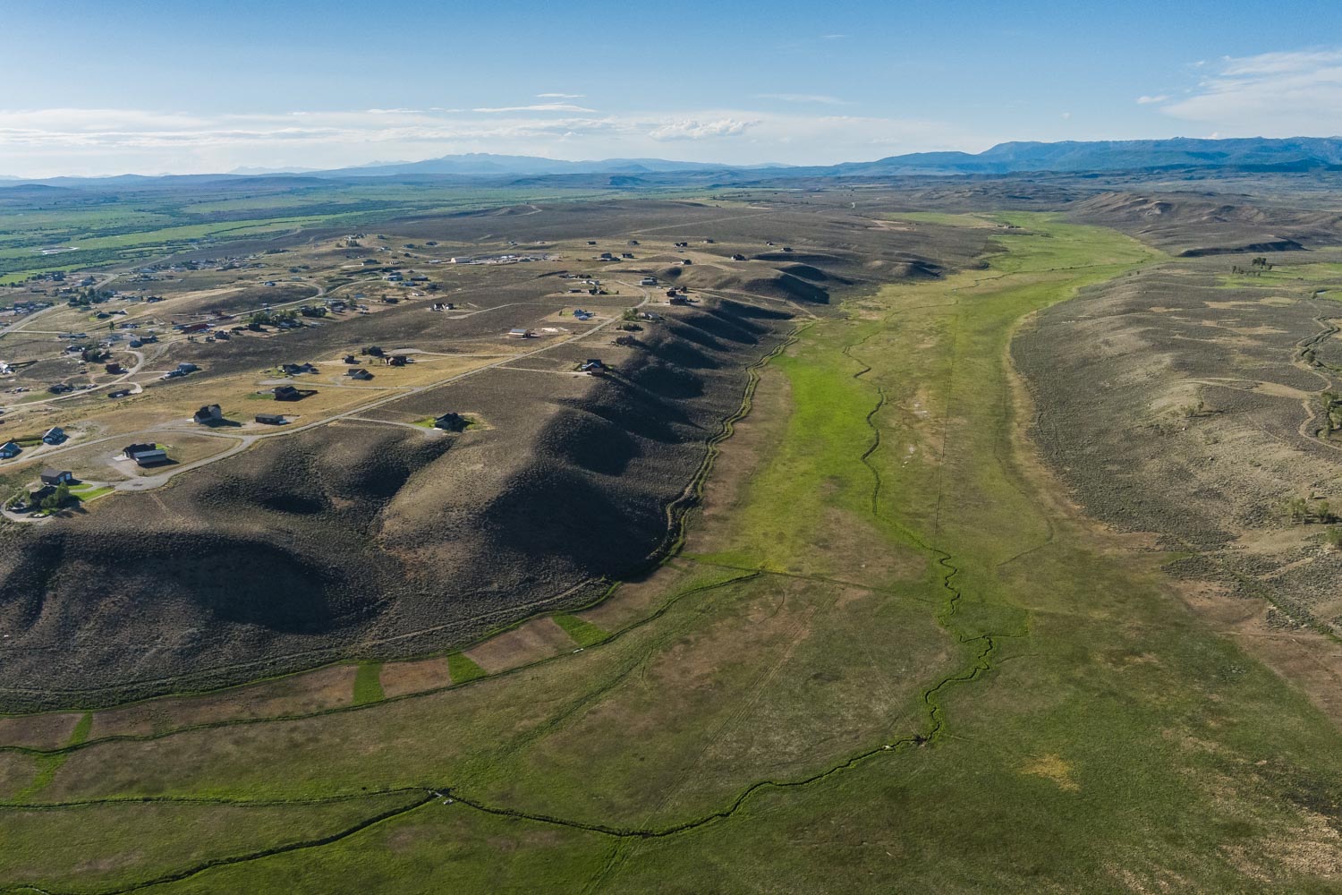 Aerial of the property's rolling topography with Pinedale beyond